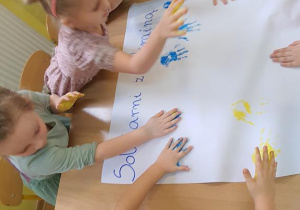 Dzieci odciskając dłonie tworzą flagę Ukrainy.